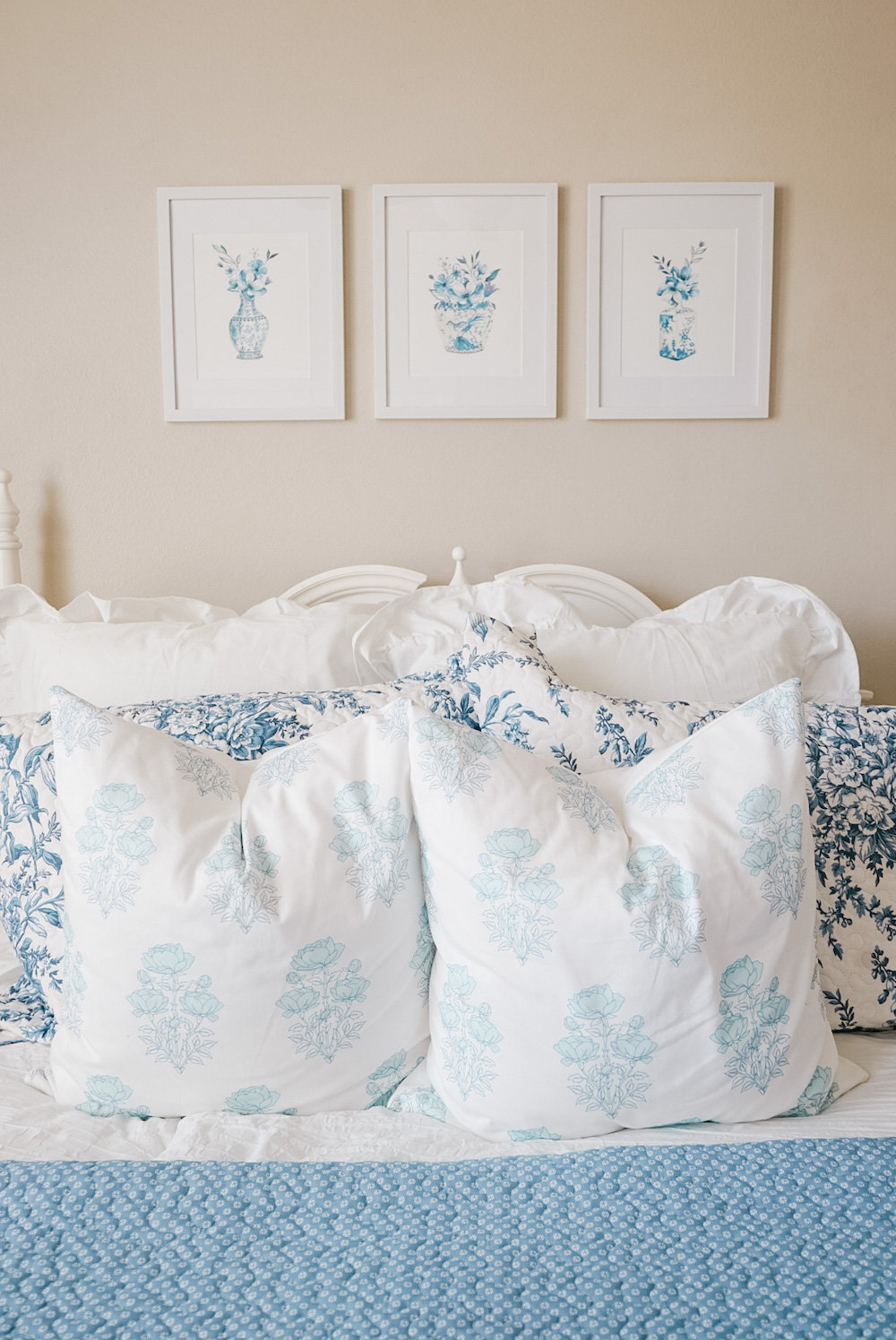 blue and white ginger jar photo prints in frames above the bed and decorative pillows