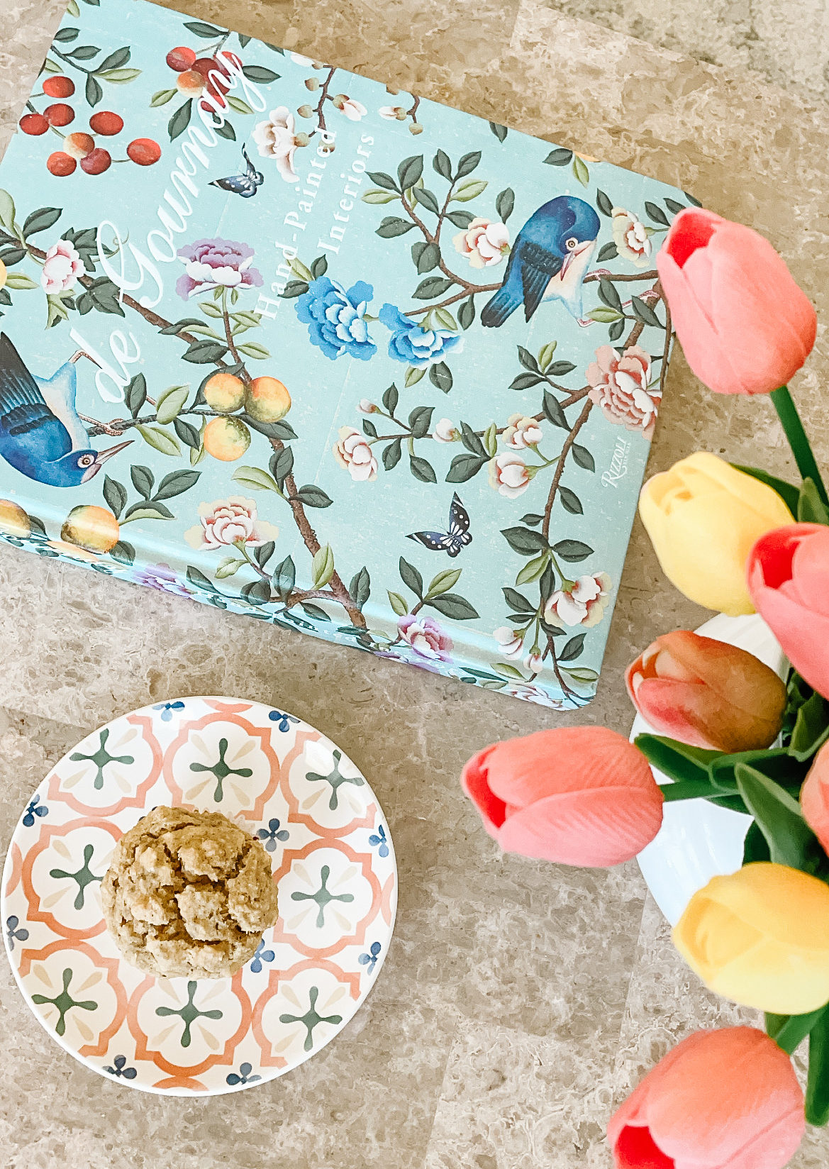 gluten free and dairy free muffin on a plate on coffee table with colorful tulips and de gournay coffee table book