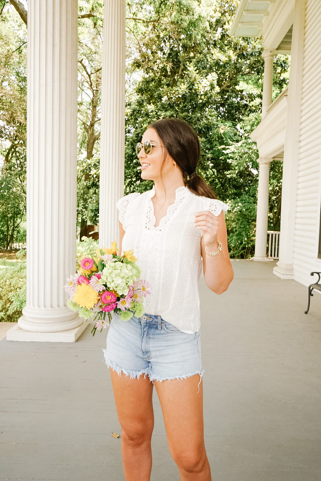 white eyelet blouse with denim shorts and fresh colorful flowers
